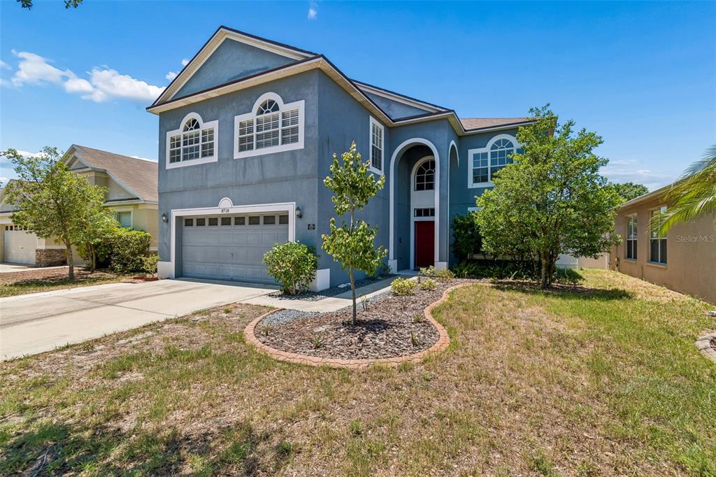 A two-story blue house with a two-car garage and a front yard with landscaping — 8718 SANDY PLAINS DRIVE, RIVERVIEW, FL
