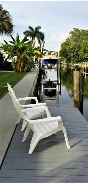 Two white plastic chairs sit on a gray wooden dock overlooking a canal with a boat — 600 JUNGLE QUEEN WAY, LONGBOAT KEY, FL
