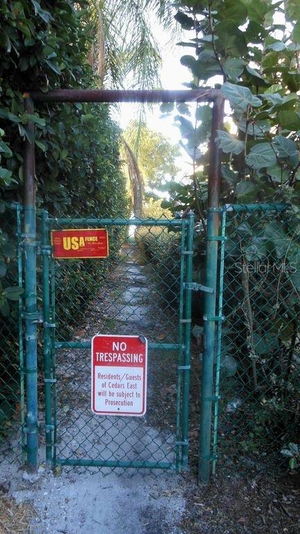 A chain-link gate with a no trespassing sign leads to a path through dense foliage — 600 JUNGLE QUEEN WAY, LONGBOAT KEY, FL