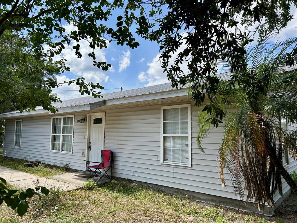 A single-story house with light-colored siding, a metal roof, and a red folding chair — 830 ALABAMA STREET, WAUCHULA, FL