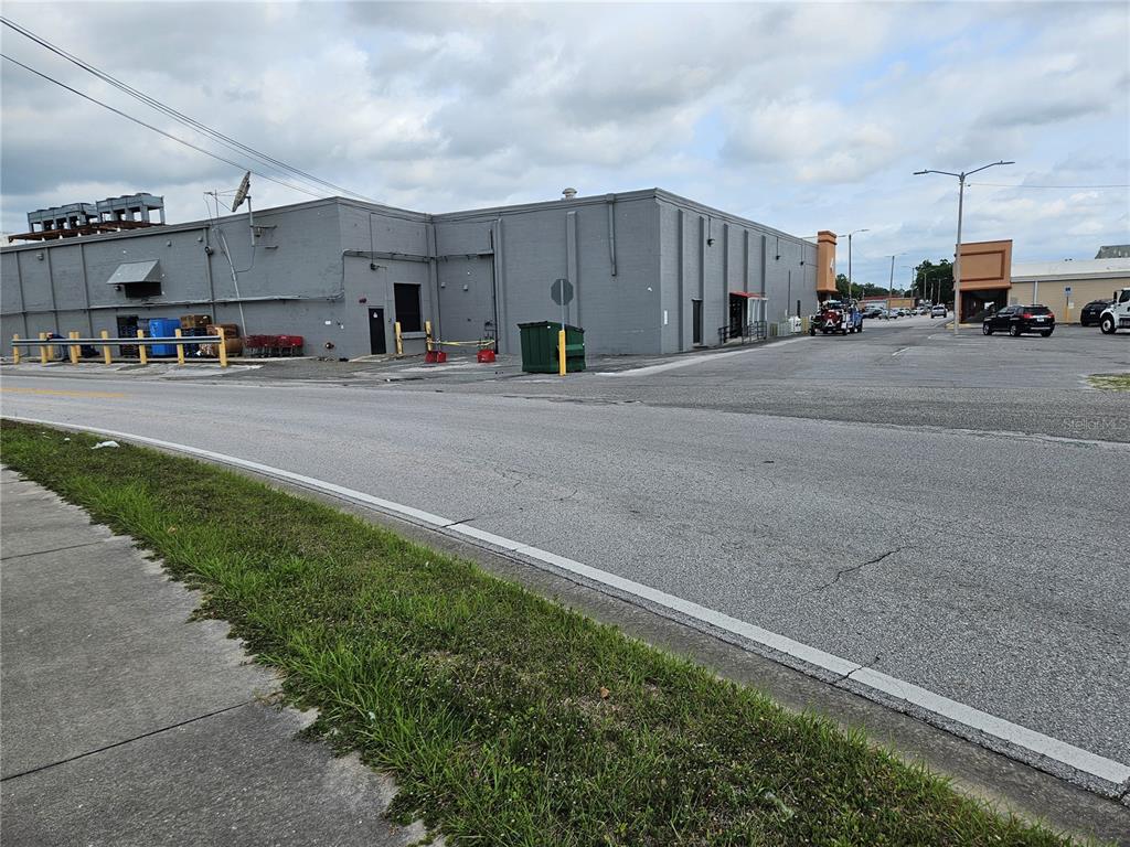 The exterior of a gray commercial building features a parking lot and a sidewalk — 204 HUEY STREET, WILDWOOD, FL
