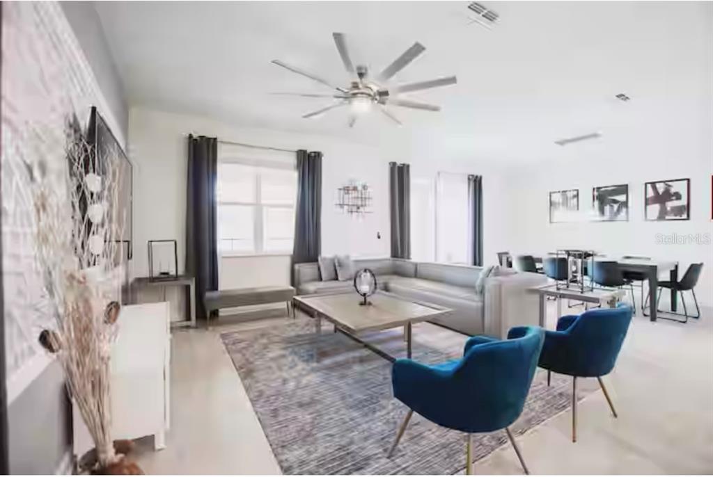A living room with a sectional sofa, two blue armchairs, and a dining area nearby — 9024 SOMMERSET HILLS DRIVE, DAVENPORT, FL