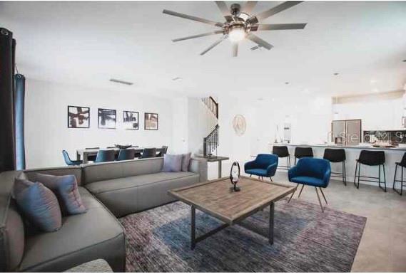 An open-concept living and dining area features a gray sectional sofa, blue chairs, and kitchen — 9024 SOMMERSET HILLS DRIVE, DAVENPORT, FL