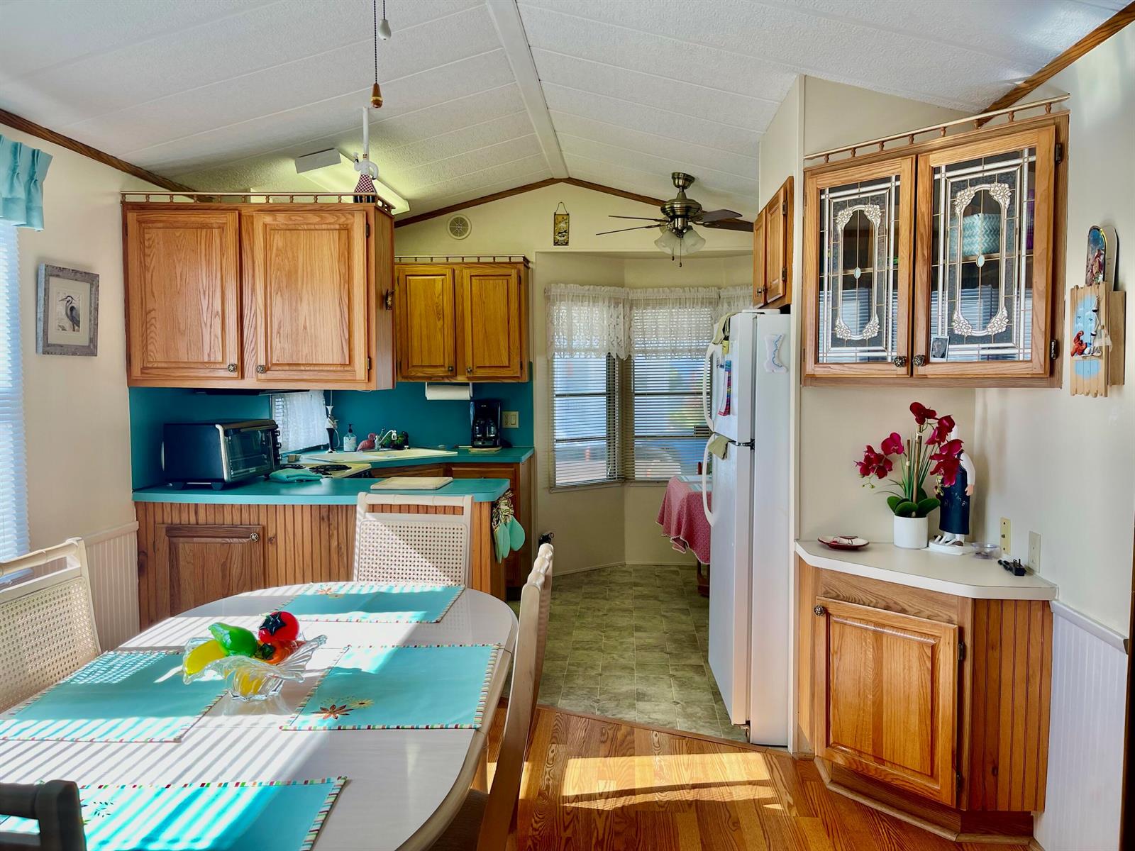 A kitchen and dining area with wood cabinets, teal countertops, and a white refrigerator — 5374 SE 64th Avenue, Okeechobee FL 34974, OKEECHOBEE, FL
