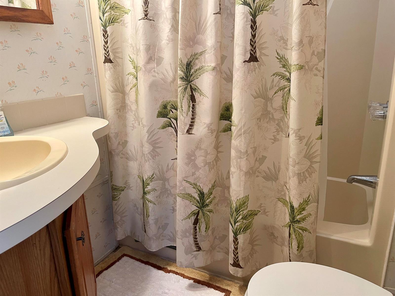 A bathroom features a palm tree print shower curtain, a vanity with a sink, and wallpaper — 5374 SE 64th Avenue, Okeechobee FL 34974, OKEECHOBEE, FL