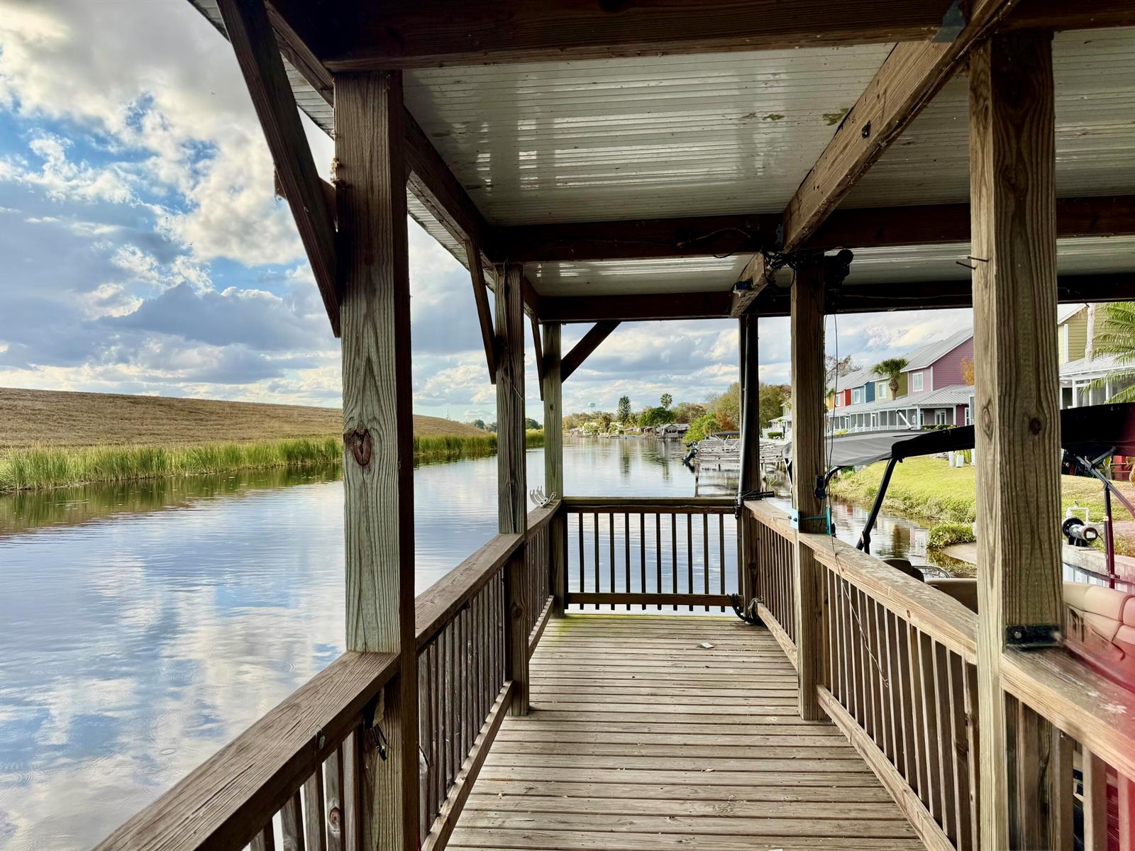 A wooden boat dock with a covered roof overlooks a calm canal and grassy bank — 4390 Us Highway 441 SE, Okeechobee FL 34974, OKEECHOBEE, FL