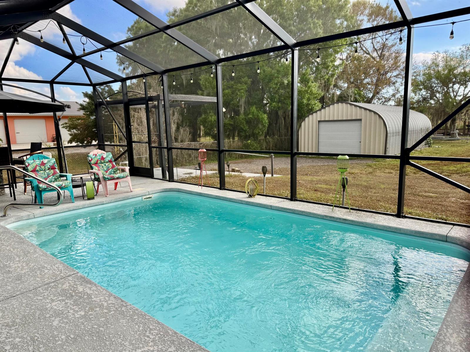 A screened-in swimming pool enclosure features a concrete deck, patio furniture, and a metal shed — 4390 Us Highway 441 SE, Okeechobee FL 34974, OKEECHOBEE, FL