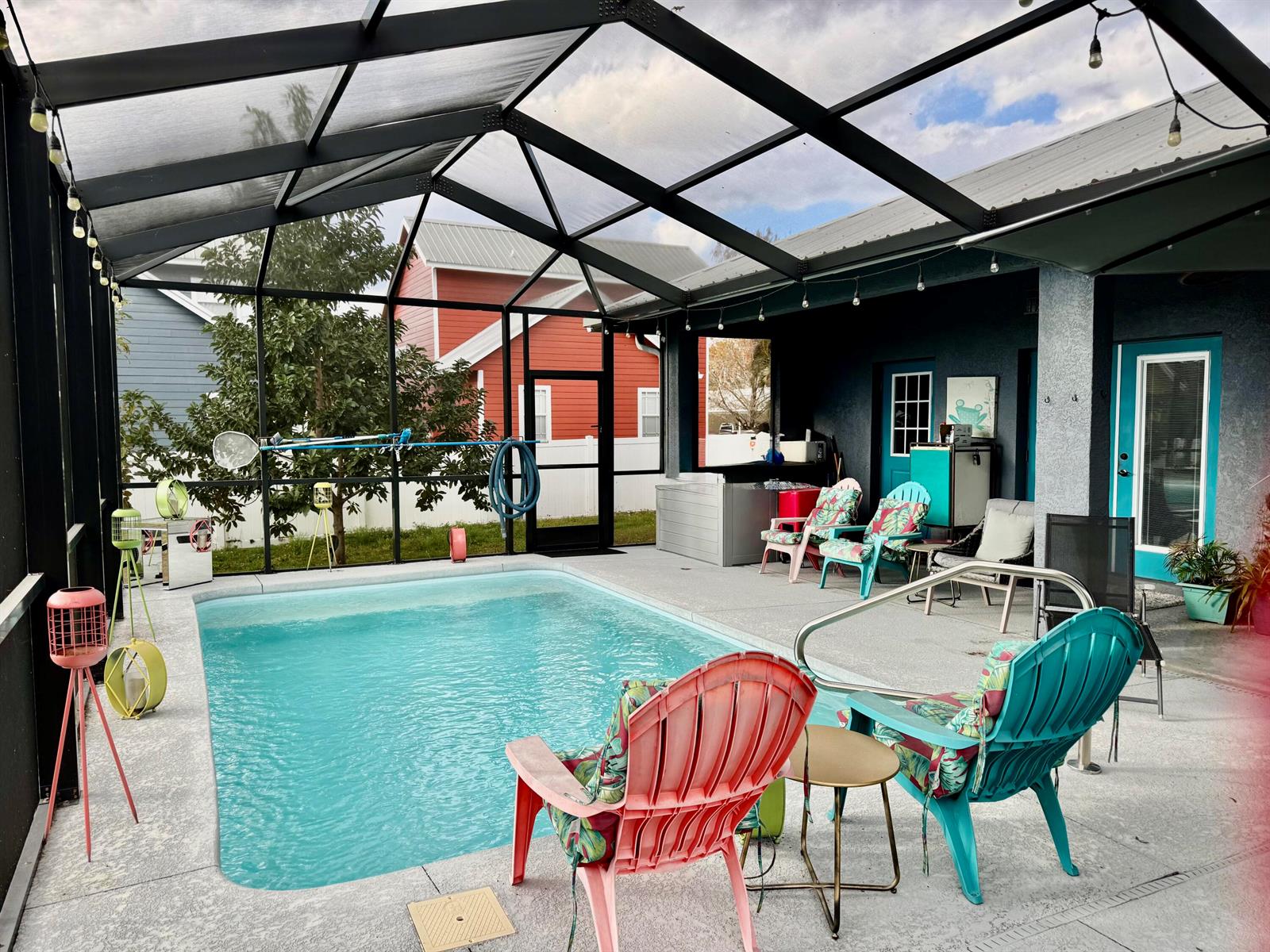 A screened-in patio features a swimming pool, colorful Adirondack chairs, and a concrete deck — 4390 Us Highway 441 SE, Okeechobee FL 34974, OKEECHOBEE, FL