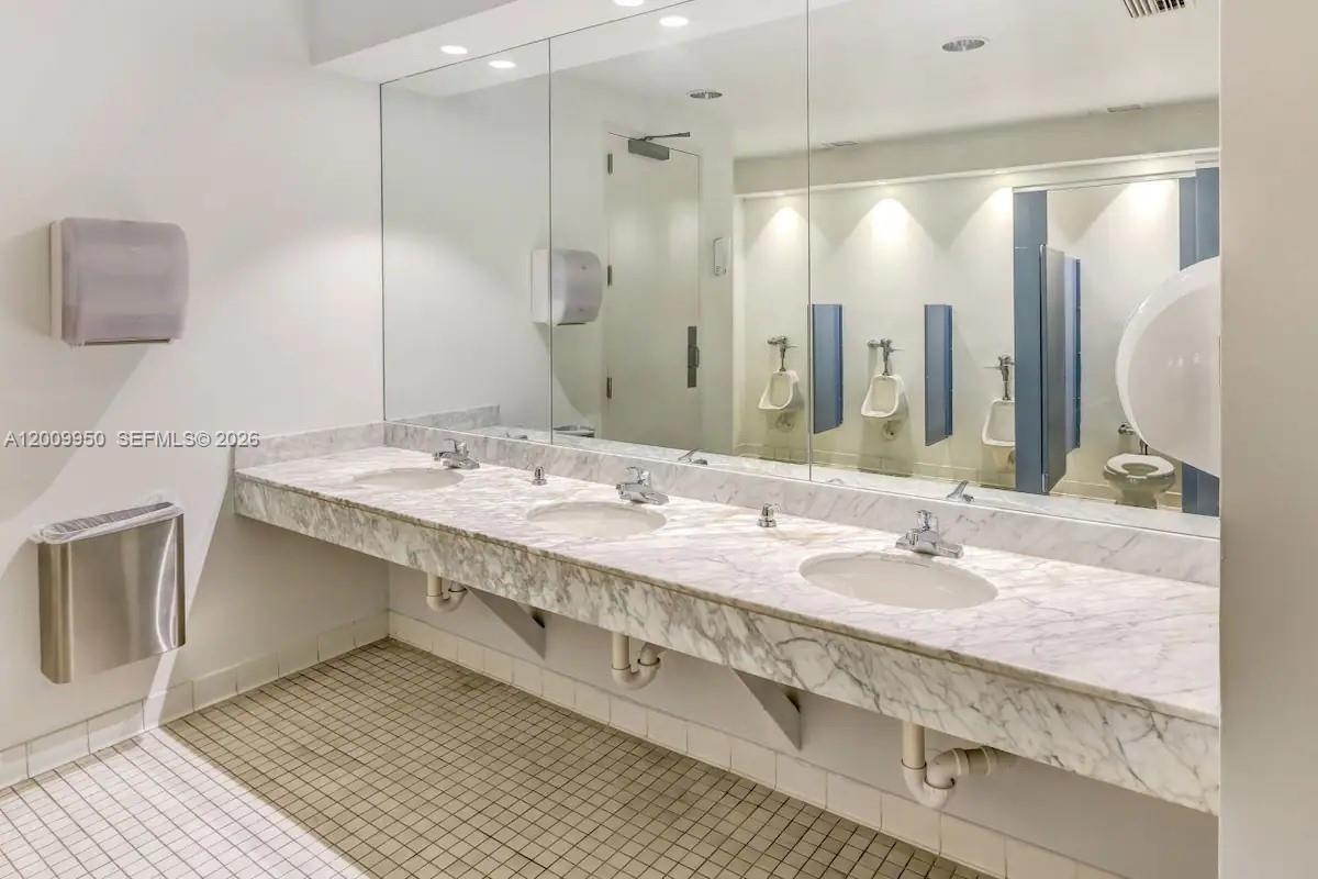 A commercial restroom features a long marble vanity with three sinks and a large mirror — 1200 Brickell Bay Dr # 1404, Miami FL 33131, MIAMI, FL