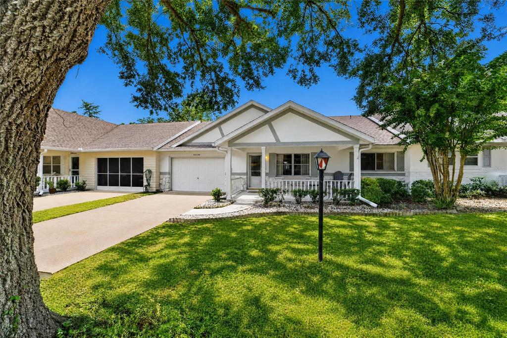 A single-story house with a white garage, front porch, and a large tree in the yard — 8526 SW 91ST STREET UNIT D, OCALA, FL