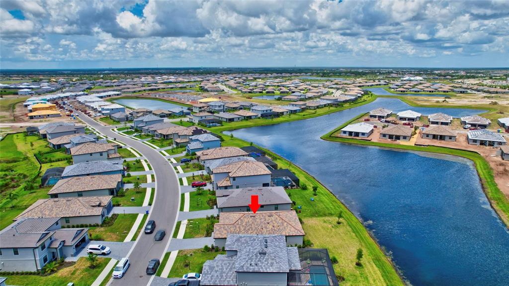 An aerial view shows a residential neighborhood with houses, a winding road, and a large lake — 5409 CORAL REEF WAY, BRADENTON, FL