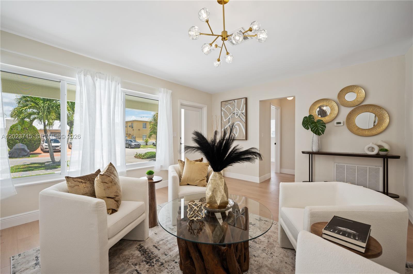 A bright living room features white armchairs, a glass-topped coffee table, and a modern chandelier — 4220 SW 14th St, Miami FL 33134, MIAMI, FL