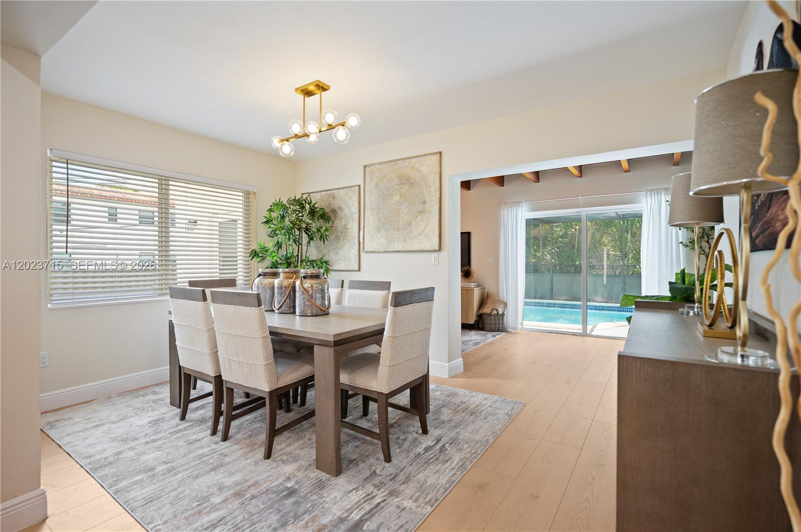 A dining room features a wooden table, upholstered chairs, a chandelier, and a pool view — 4220 SW 14th St, Miami FL 33134, MIAMI, FL