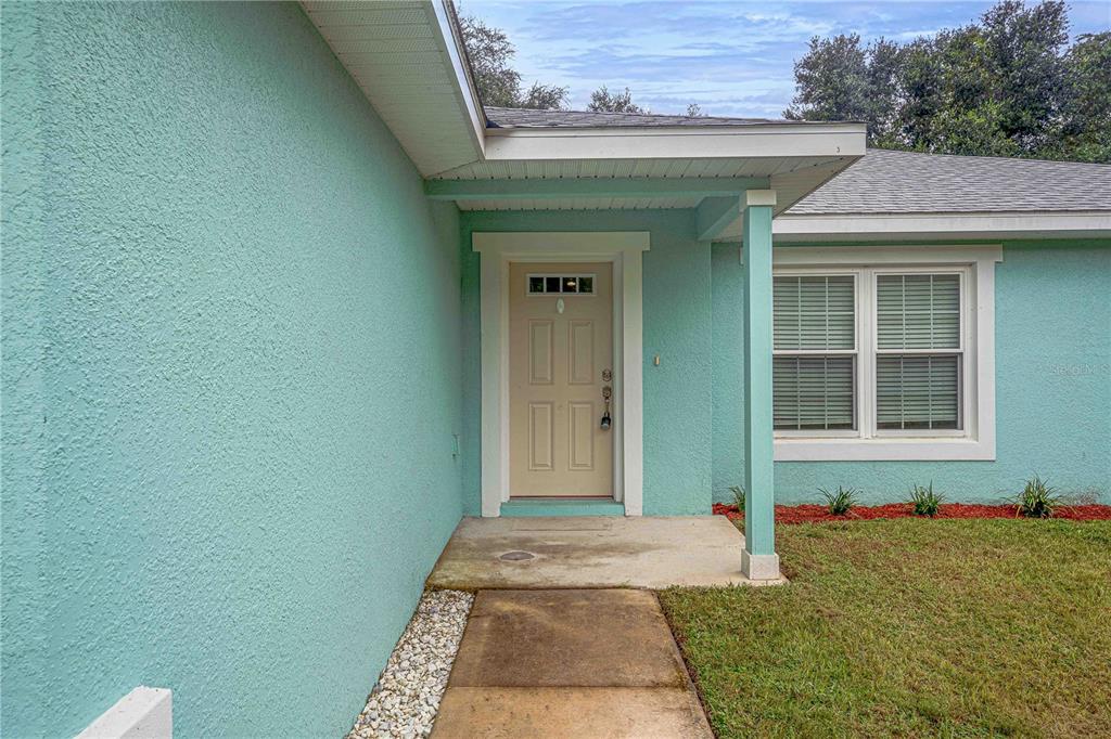 A teal exterior wall features a beige front door under a covered entryway — 7752 N WALTON TERRACE, CITRUS SPRINGS, FL