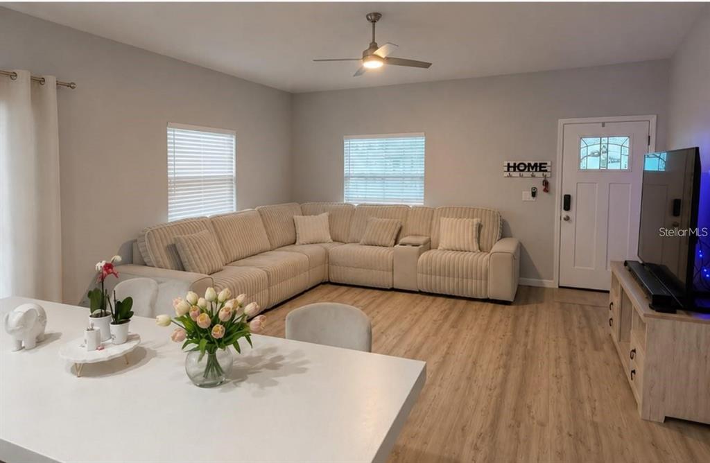 A living room features a large beige sectional sofa, light wood flooring, and a dining area — 617 HOLMES AVENUE, DAYTONA BEACH, FL