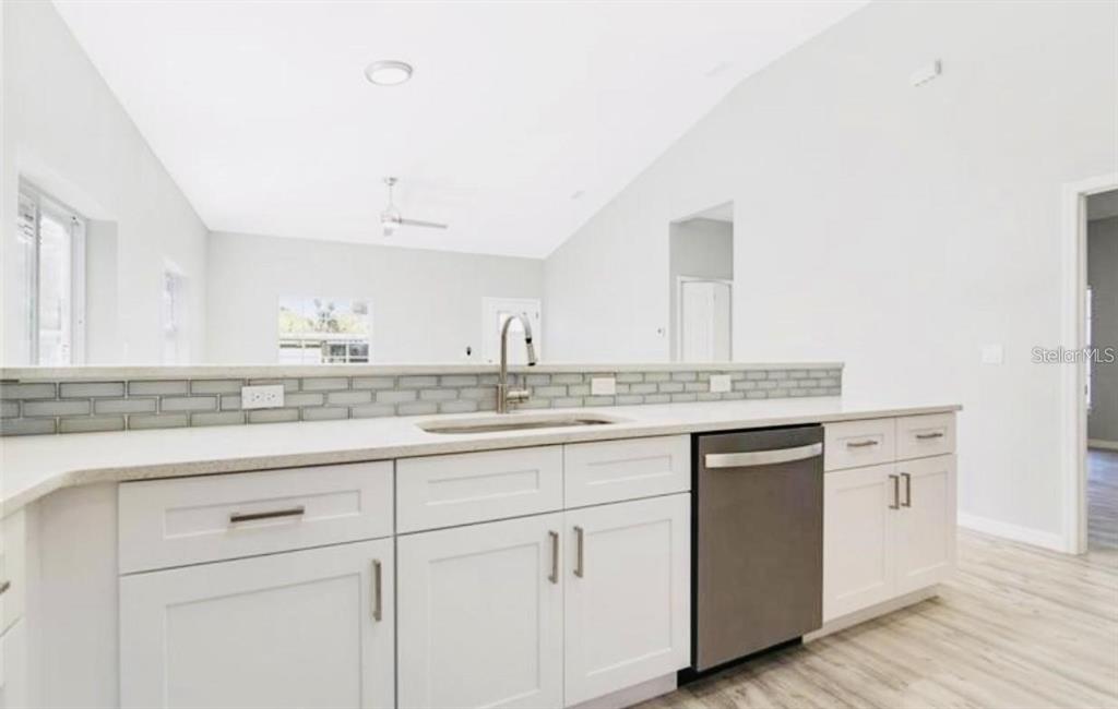 A kitchen features white cabinets, a stainless steel dishwasher, and a gray subway tile backsplash — 617 HOLMES AVENUE, DAYTONA BEACH, FL