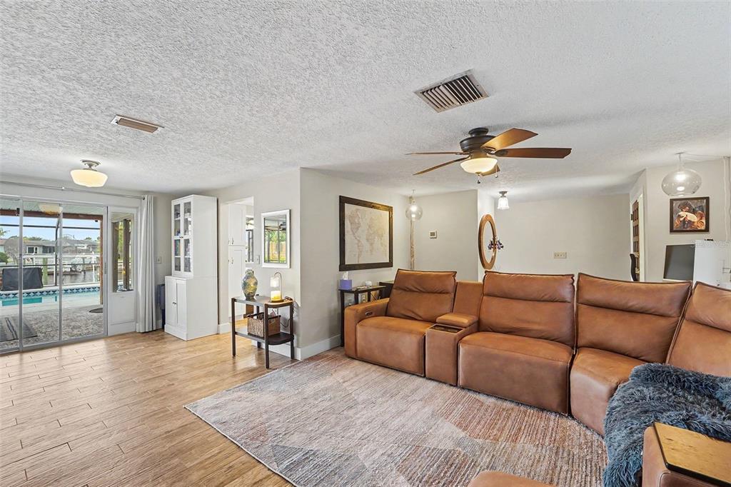 A living room features a brown leather sectional, a patterned rug, and sliding glass doors — 5736 MELALEUCA DRIVE, HOLIDAY, FL