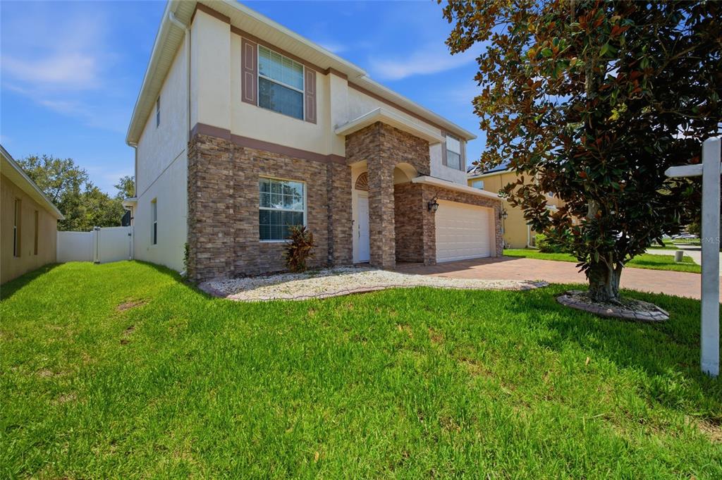 A two-story house with a stone facade, a two-car garage, and a front lawn — 12407 GILMERTON MIST LANE, RIVERVIEW, FL