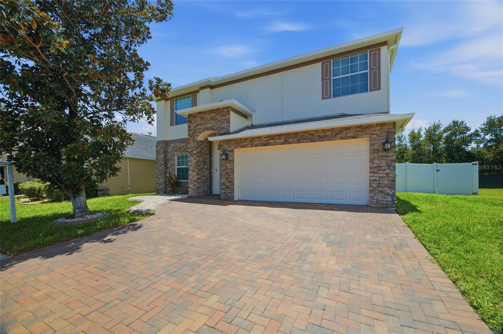 A two-story house with a stone facade, a paved driveway, and a two-car garage — 12407 GILMERTON MIST LANE, RIVERVIEW, FL