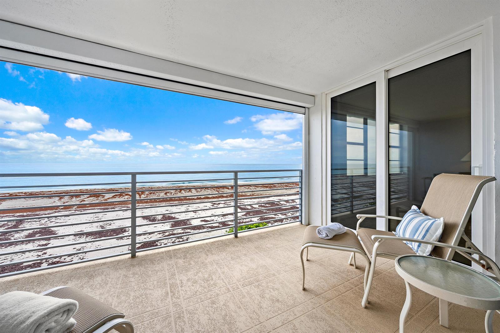 A balcony with tile flooring, patio furniture, and a direct view of the ocean — 900 Ocean Drive # 202, Juno Beach FL 33408, JUNO BEACH, FL