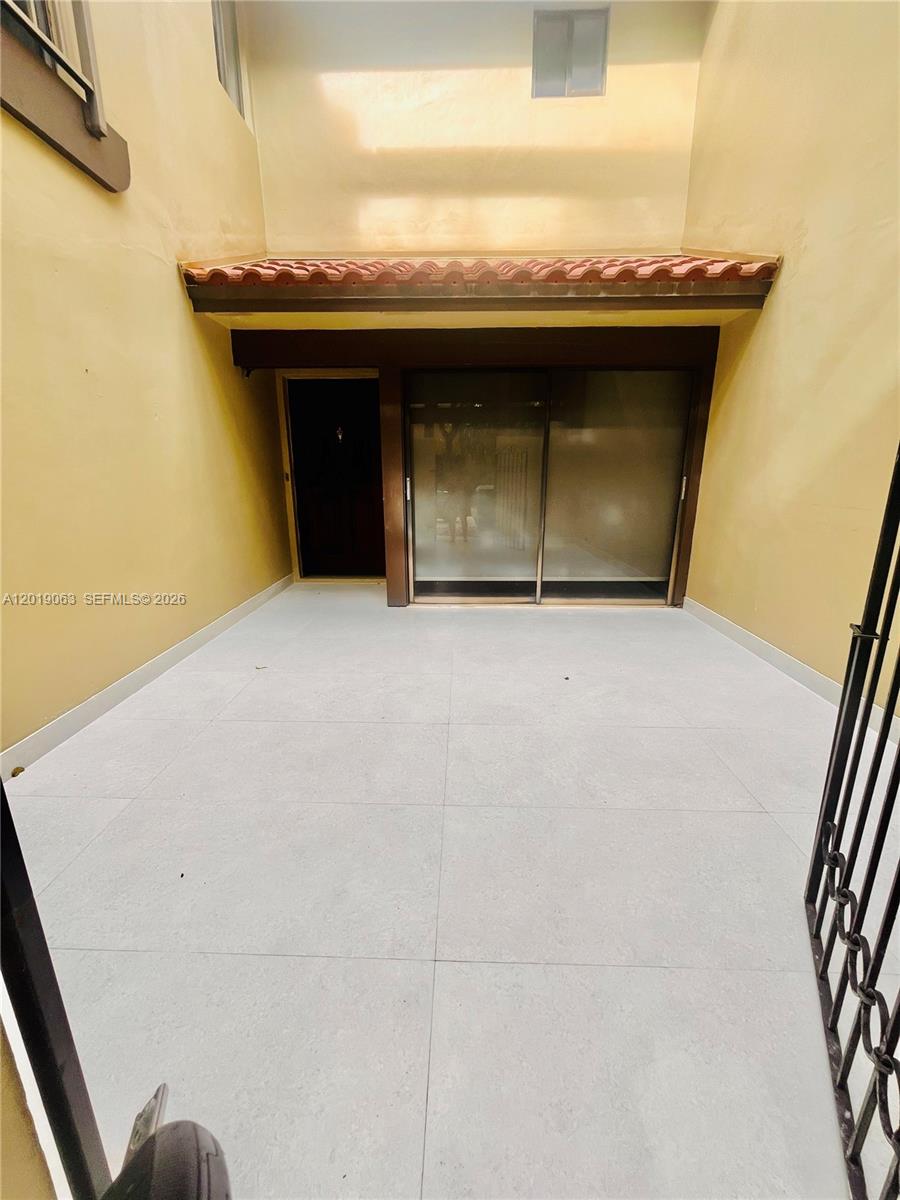 A paved outdoor patio features a sliding glass door and a small entrance door — 3643 Estepona Ave # A, Doral FL 33178, DORAL, FL