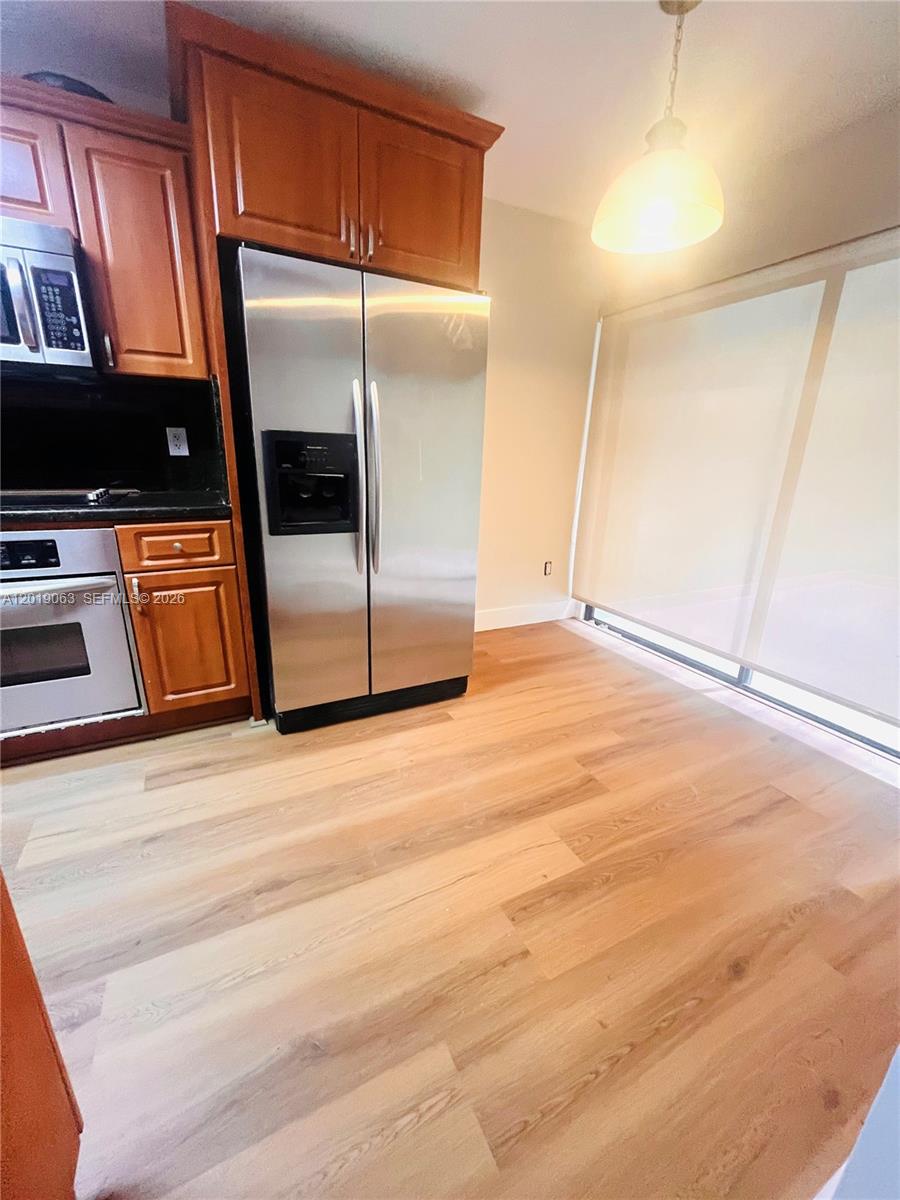 A kitchen features wood cabinets, stainless steel appliances, and light wood-look flooring — 3643 Estepona Ave # A, Doral FL 33178, DORAL, FL