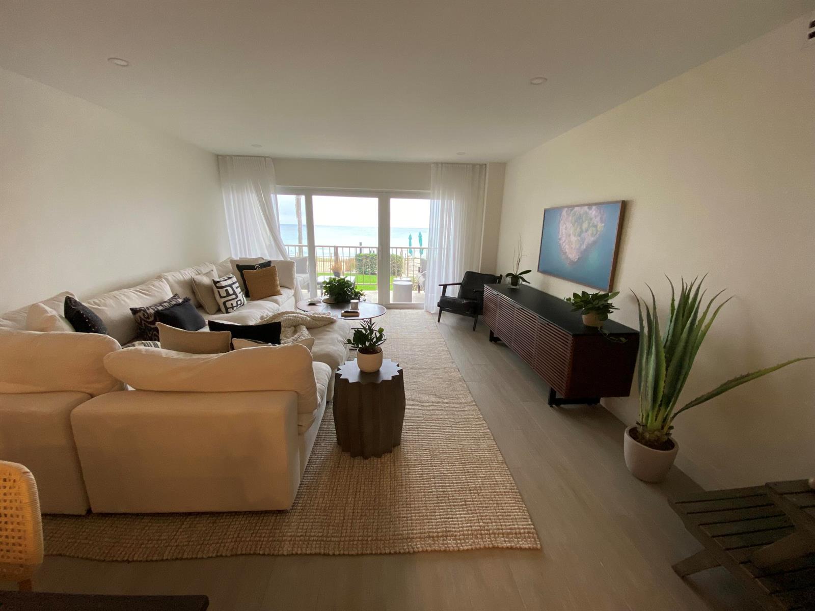 A living room features a large white sectional, a wooden media console, and ocean views — 1021 Hillsboro Mile # G6, Hillsboro Beach FL 33064, HILLSBORO BEACH, FL