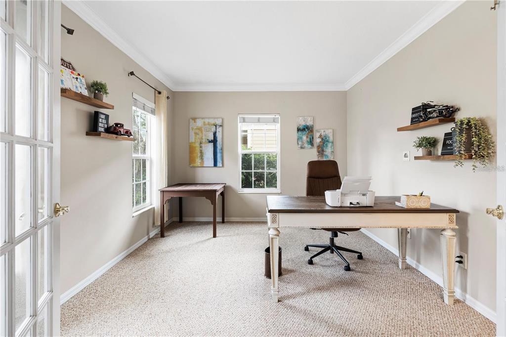 A home office with beige walls, carpeted floors, two desks, and wall-mounted shelving — 932 PAWSTAND ROAD, CELEBRATION, FL