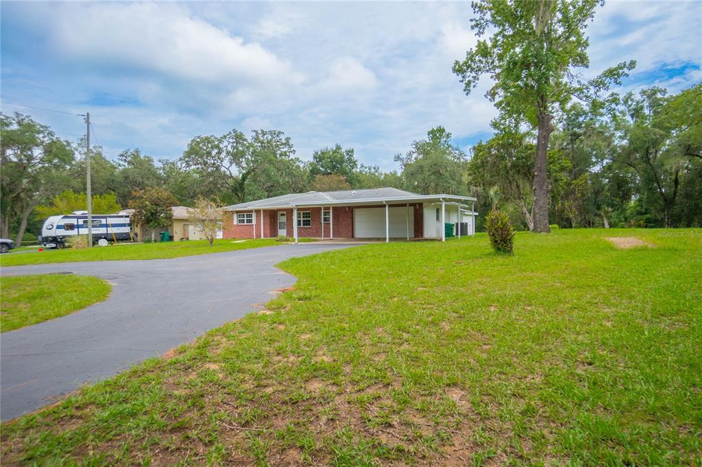A single-story brick house with a carport and a large front lawn — 1919 FOREST DRIVE, INVERNESS, FL