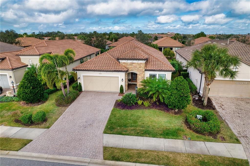 An aerial view of a single-story suburban house with a tiled roof and paved driveway — 13031 PALERMO DRIVE, BRADENTON, FL