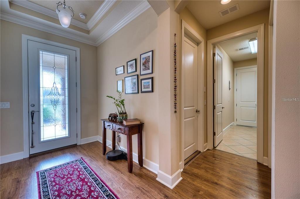An entryway features a wood floor, a patterned rug, a console table, and framed wall art — 13031 PALERMO DRIVE, BRADENTON, FL