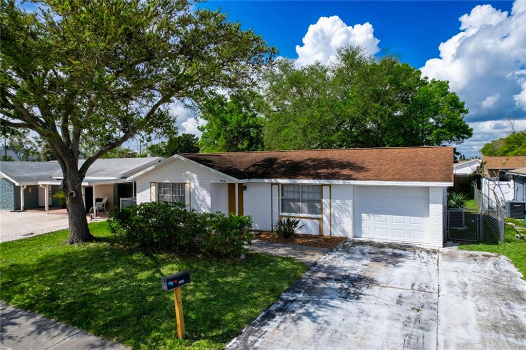 A single-story white brick house with a brown roof and a one-car garage — 9741 LAMANTIN DRIVE, PORT RICHEY, FL