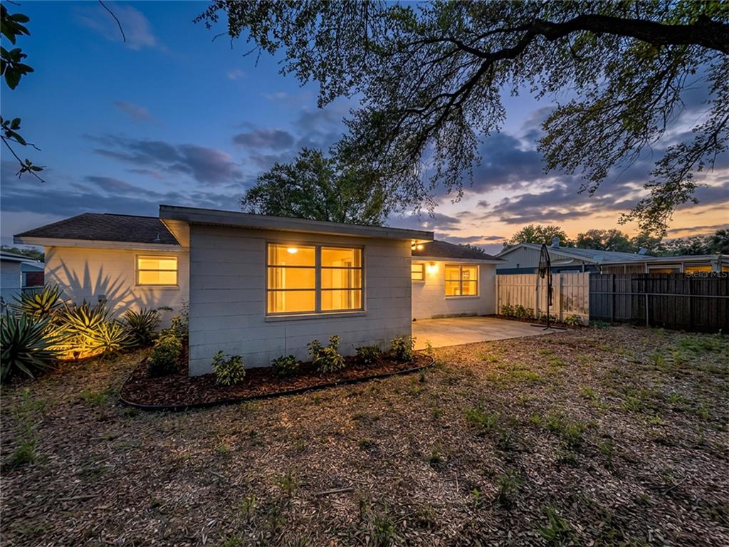 The exterior of a single-story house at dusk features a concrete block wall and patio — 9741 LAMANTIN DRIVE, PORT RICHEY, FL