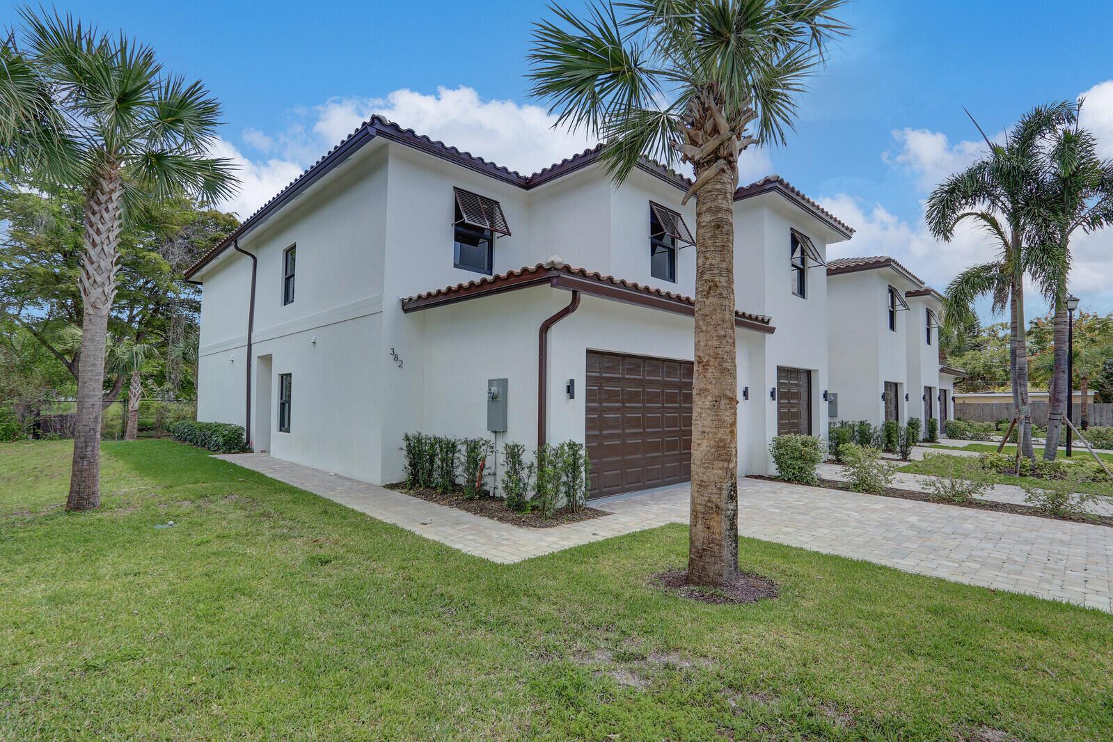 A two-story white townhouse with a brown garage door and palm trees in the yard — 406 Bella Sol Way, West Palm Beach FL 33406, WEST PALM BEACH, FL