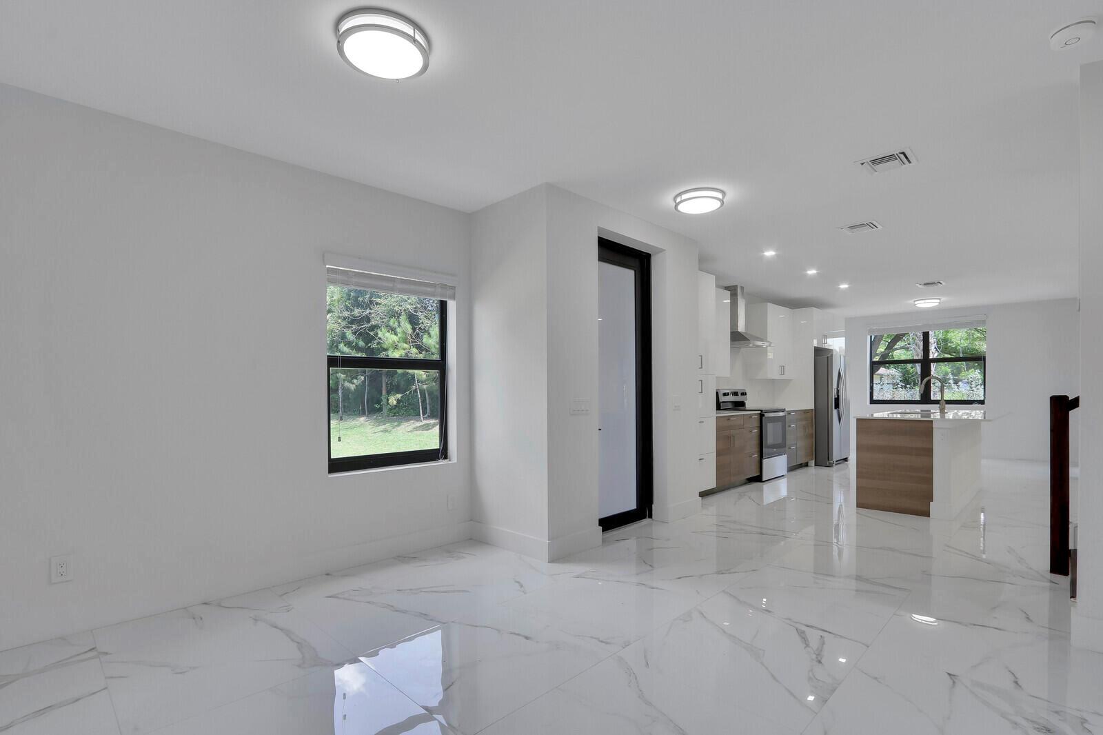 A bright kitchen and dining area features white walls, marble-look tile floors, and wood cabinetry — 406 Bella Sol Way, West Palm Beach FL 33406, WEST PALM BEACH, FL