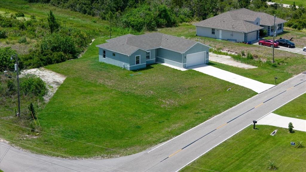 An aerial view shows a light blue single-story house with a garage and large yard — 1911 RICHMOND AVENUE N, LEHIGH ACRES, FL