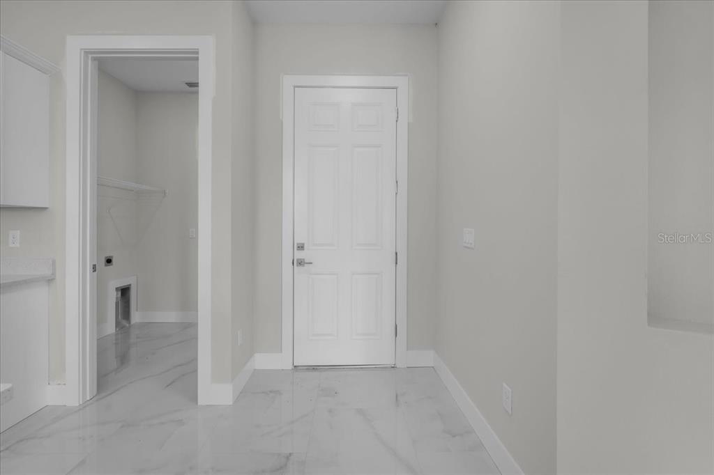 A laundry room with white tile flooring, a white door, and a utility closet — 1911 RICHMOND AVENUE N, LEHIGH ACRES, FL