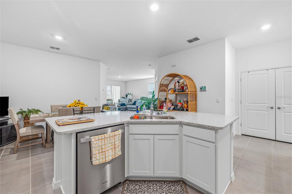 A kitchen island with a stainless steel dishwasher and sink sits in an open-concept room — 2541 BENDING BONSAI DRIVE, WESLEY CHAPEL, FL