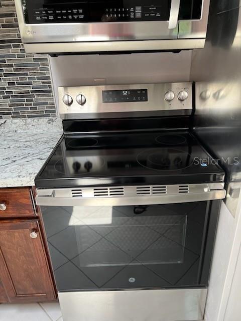 A stainless steel electric range and microwave are installed in a kitchen with dark cabinets — 53 21ST TERRACE SE, LARGO, FL