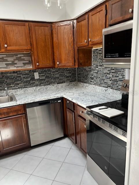 A kitchen features wood cabinets, granite countertops, stainless steel appliances, and a tiled backsplash — 53 21ST TERRACE SE, LARGO, FL