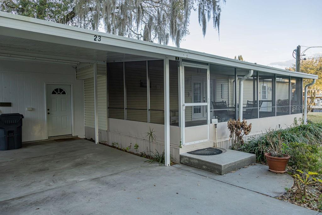 A mobile home exterior features a carport, a screened-in porch, and a concrete driveway — 23 ANCHOR INN ROAD, LAKE WALES, FL