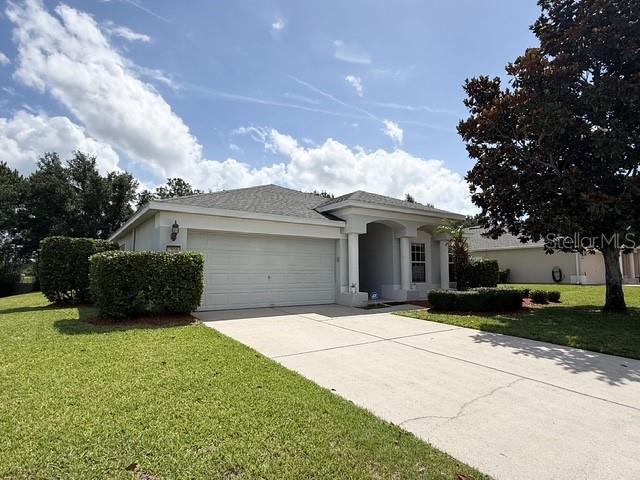 A single-story house with a two-car garage, a concrete driveway, and manicured landscaping — 2956 SANTA MARIA AVENUE, CLERMONT, FL