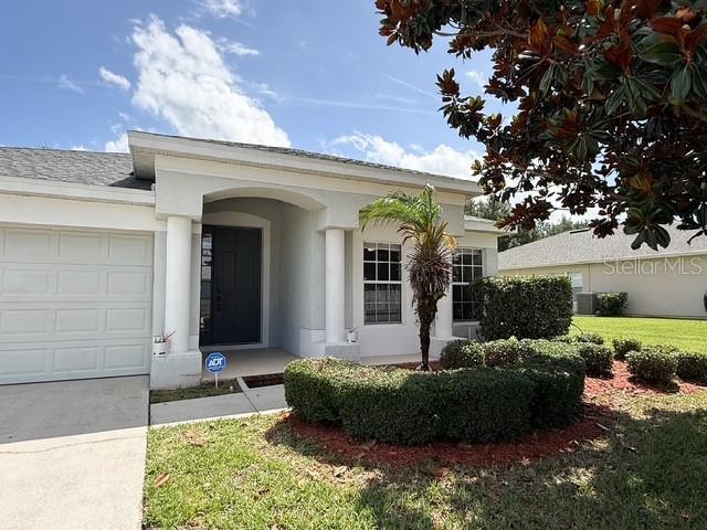 A light-colored single-story house features a garage, a front porch, and a manicured hedge — 2956 SANTA MARIA AVENUE, CLERMONT, FL