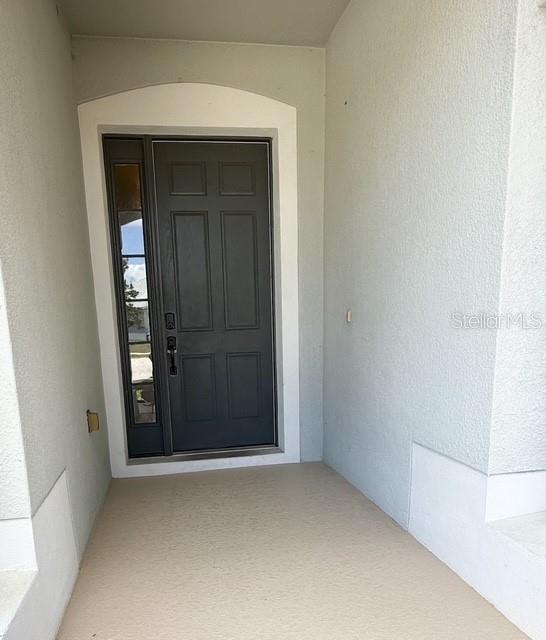 A dark gray front door with a side window sits under an arched entryway — 2956 SANTA MARIA AVENUE, CLERMONT, FL