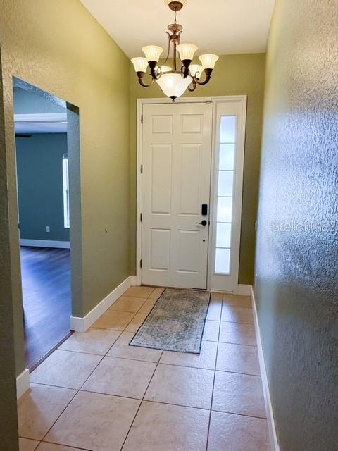A tiled entryway features a white front door, a chandelier, and a view into another room — 2956 SANTA MARIA AVENUE, CLERMONT, FL