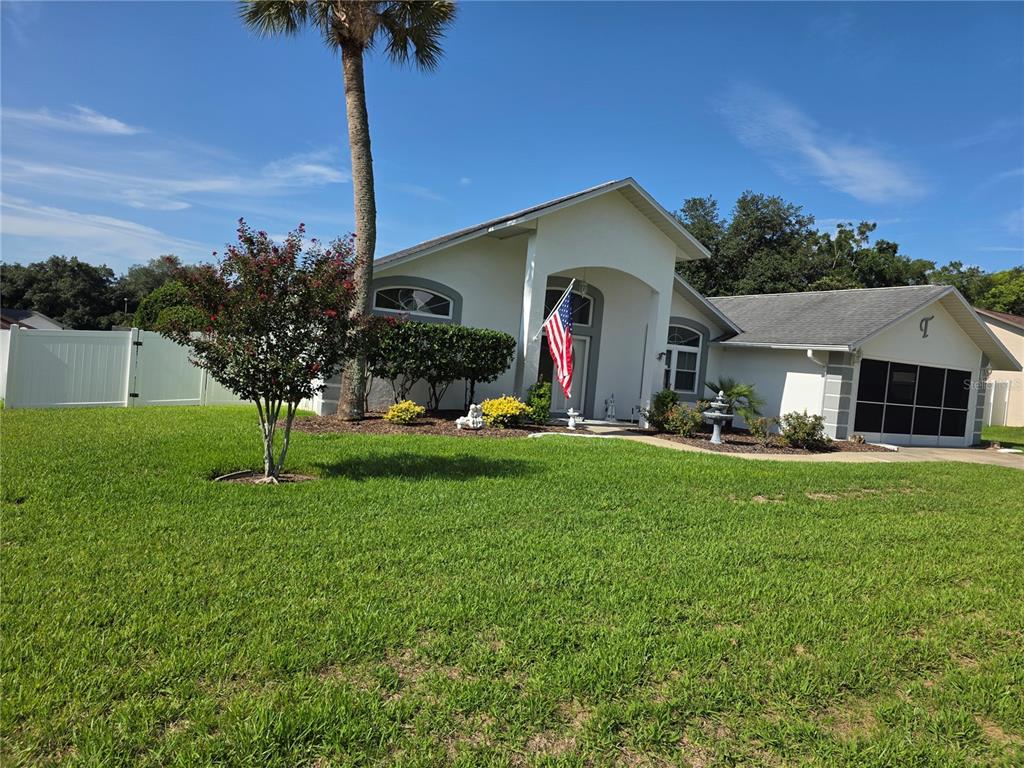 A single-story house with a white exterior, a palm tree, and an American flag — 3850 SE 59TH PLACE, OCALA, FL