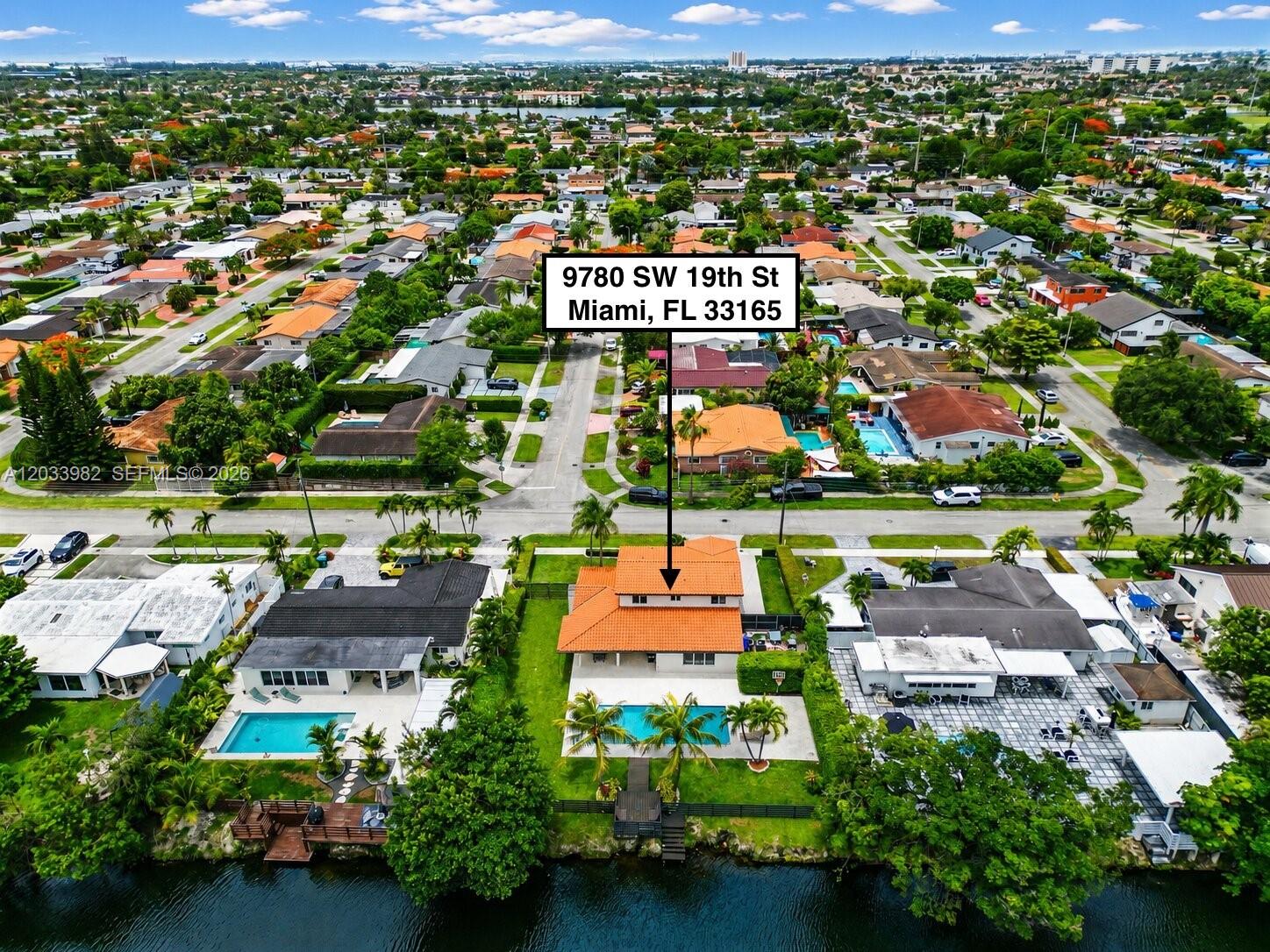 An aerial view shows a house with an orange tile roof, pool, and waterfront backyard — 9780 SW 19th St, Miami FL 33165, MIAMI, FL