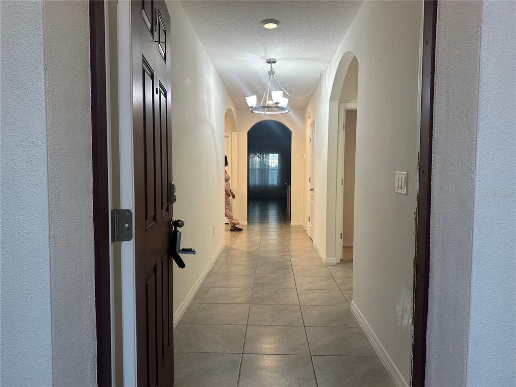 A tiled entryway leads down a hallway toward a living area with an arched opening — 1454 MARY BELLE AVENUE, KISSIMMEE, FL