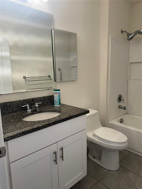 A bathroom features a white vanity with a granite countertop, a toilet, and a tub — 1454 MARY BELLE AVENUE, KISSIMMEE, FL