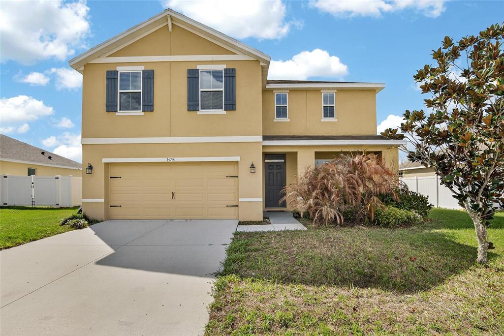 A two-story yellow house with a two-car garage and a front yard — 35716 HILLBROOK AVENUE, ZEPHYRHILLS, FL